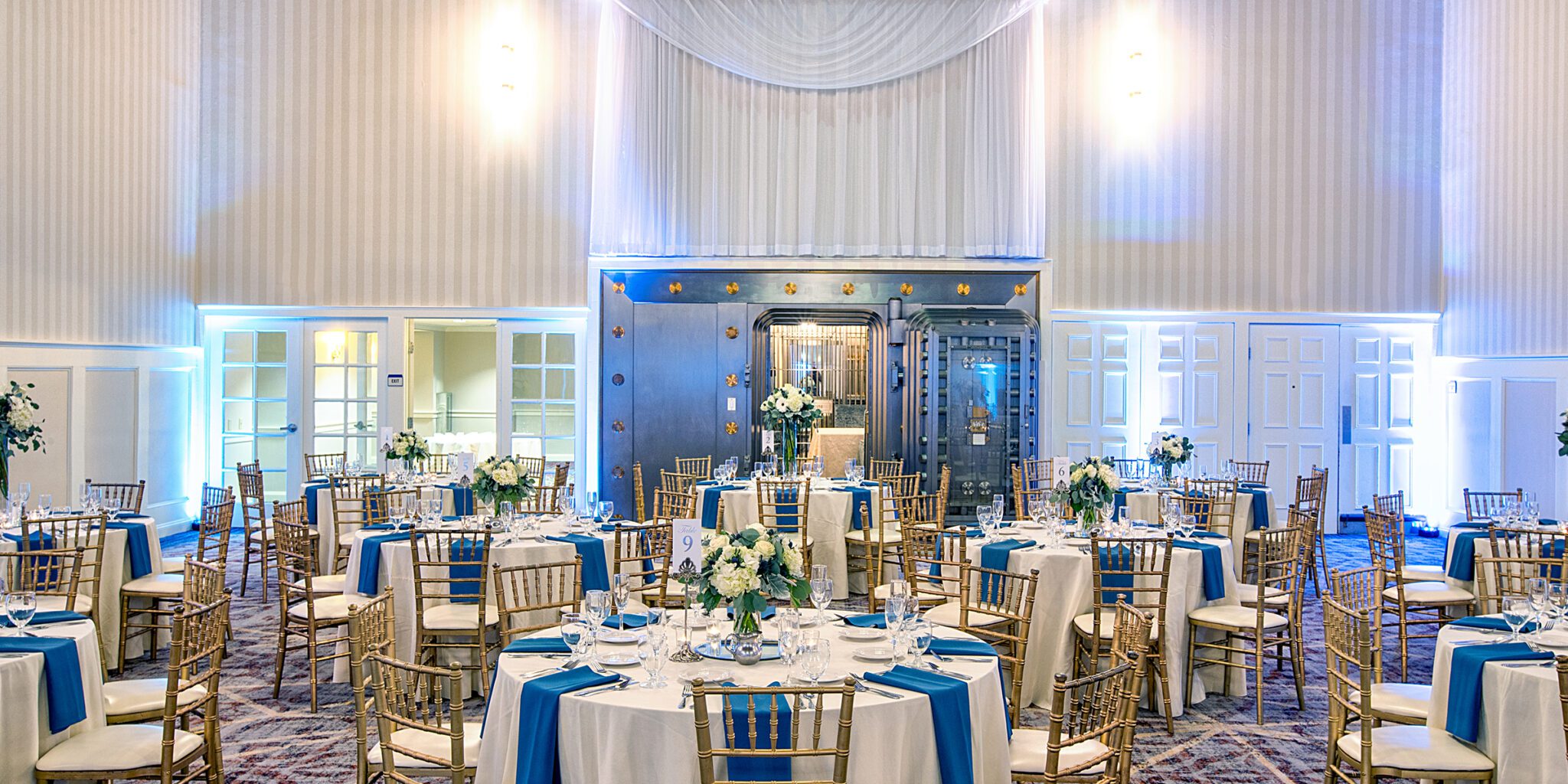 Elegant wedding reception setup with round tables, blue accents, and floral centerpieces