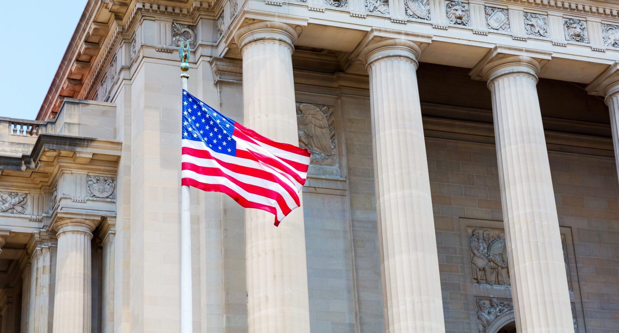American flag waving in front of a historic building with tall columns.