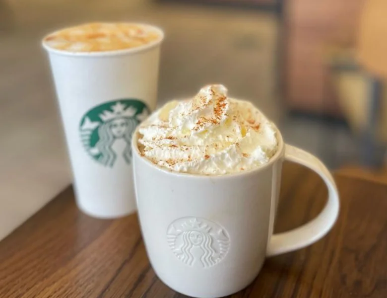 Two Starbucks drinks, one in a white paper cup and the other in a ceramic mug