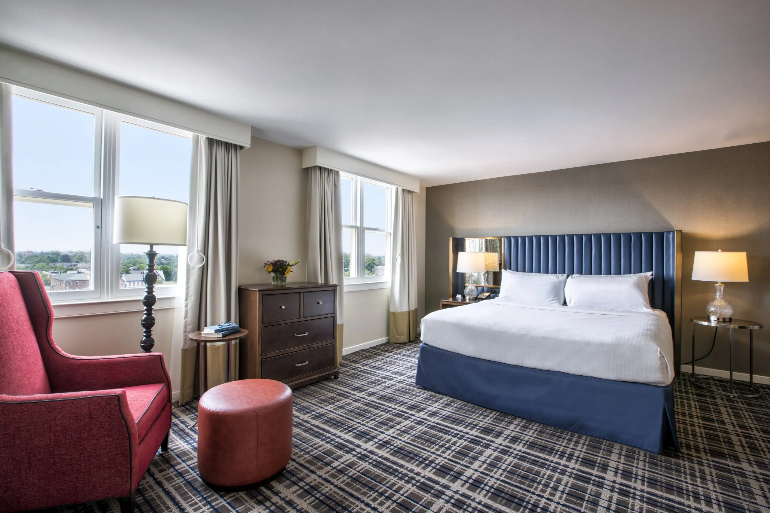 Bright and spacious guest room with a king bed, red chair, and large windows at Gettysburg Hotel